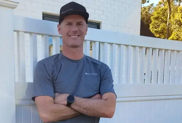 Real Fencing team member in front of a completed white fence